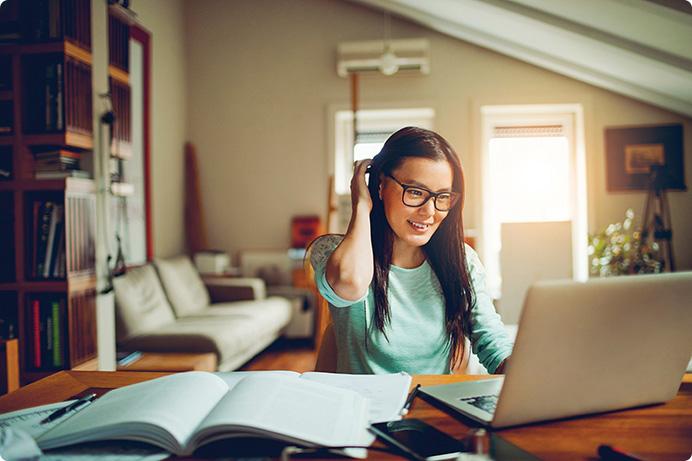 a woman sitting at a table with a laptop and books