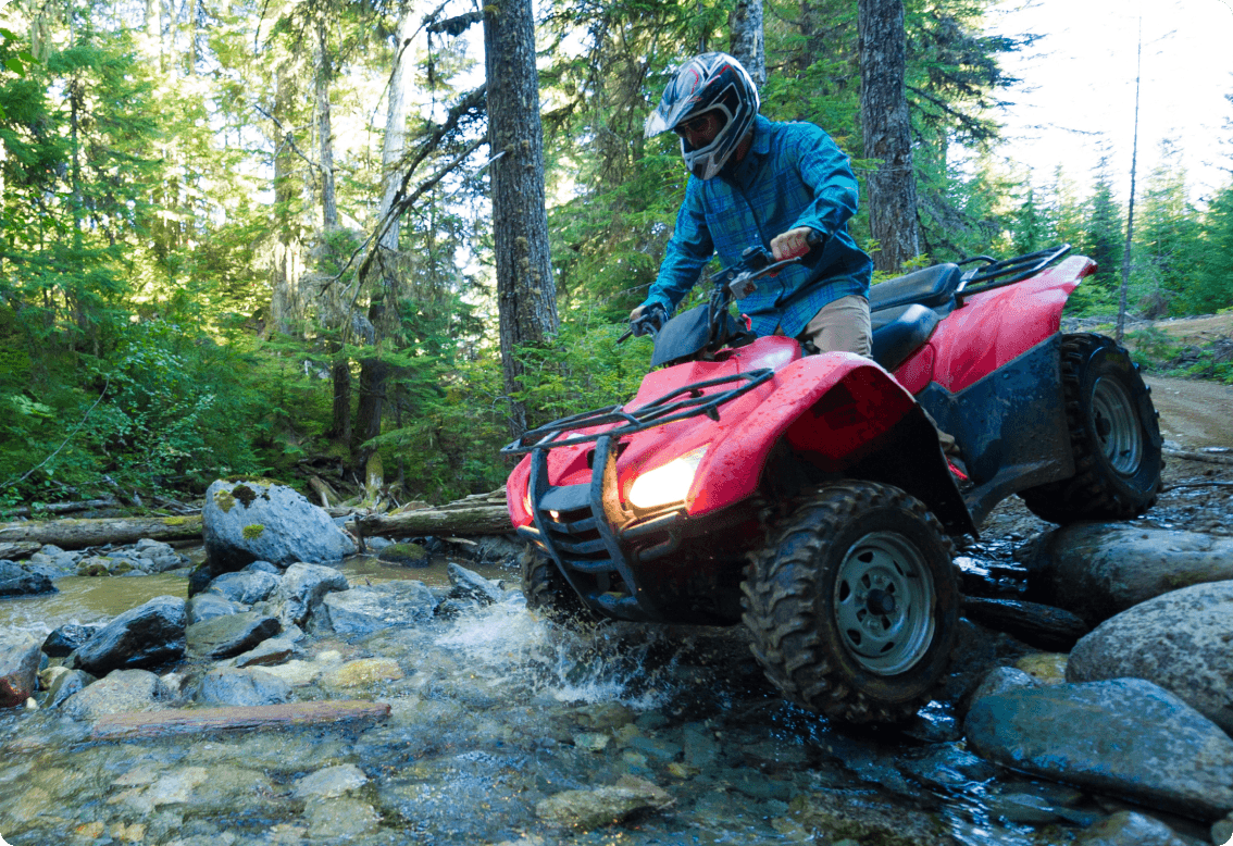 A rider riding an atv in a stream