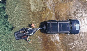 A truck backing a boat into a water.