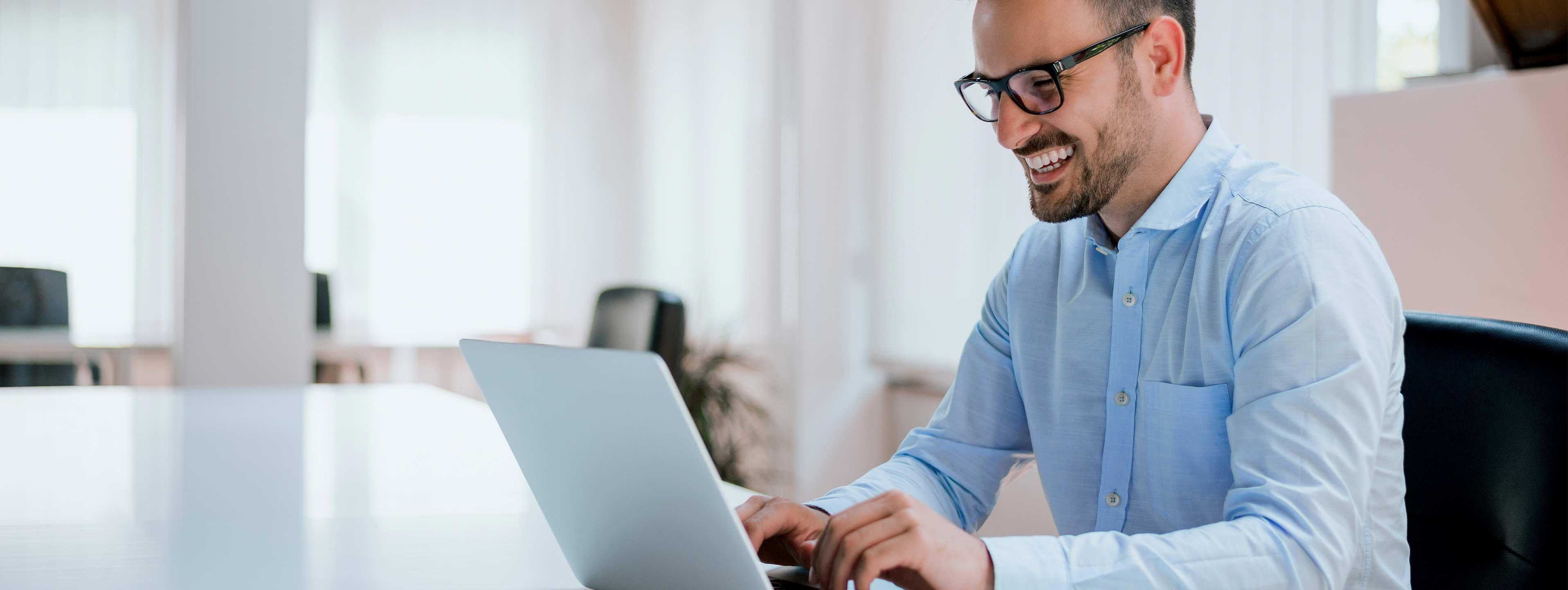 a man smiling while using a laptop