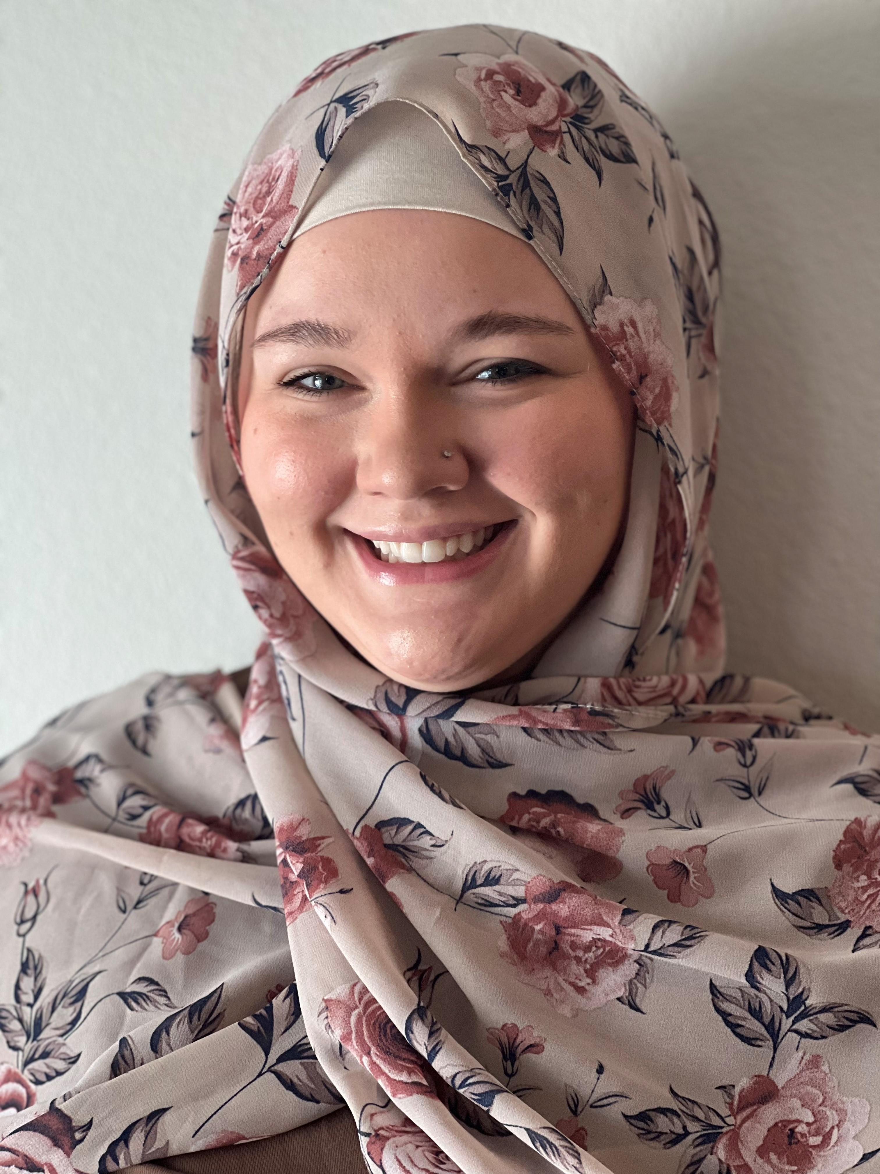 a smiling woman wearing a head scarf