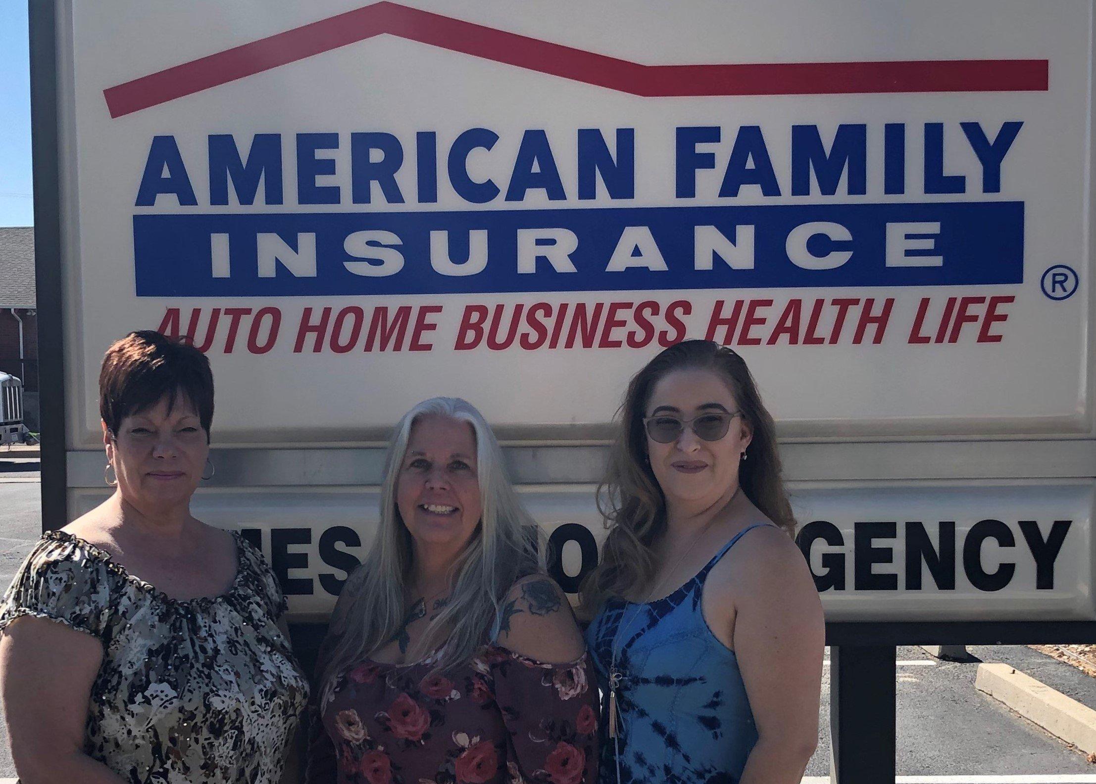 a group of women posing for a photo in front of a sign