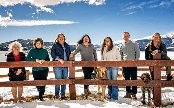 a group of people standing on a fence with dogs