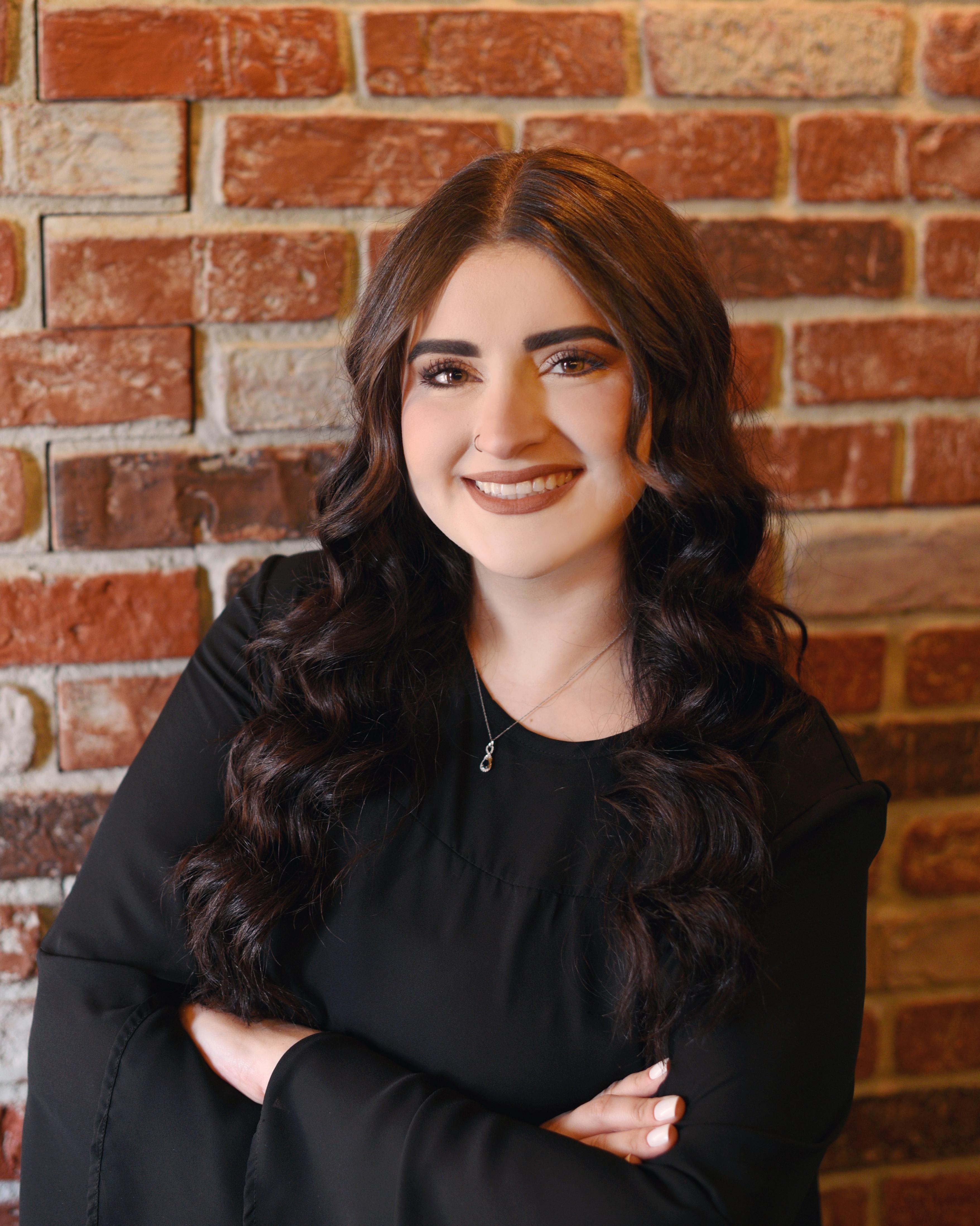 a woman smiling in front of a brick wall