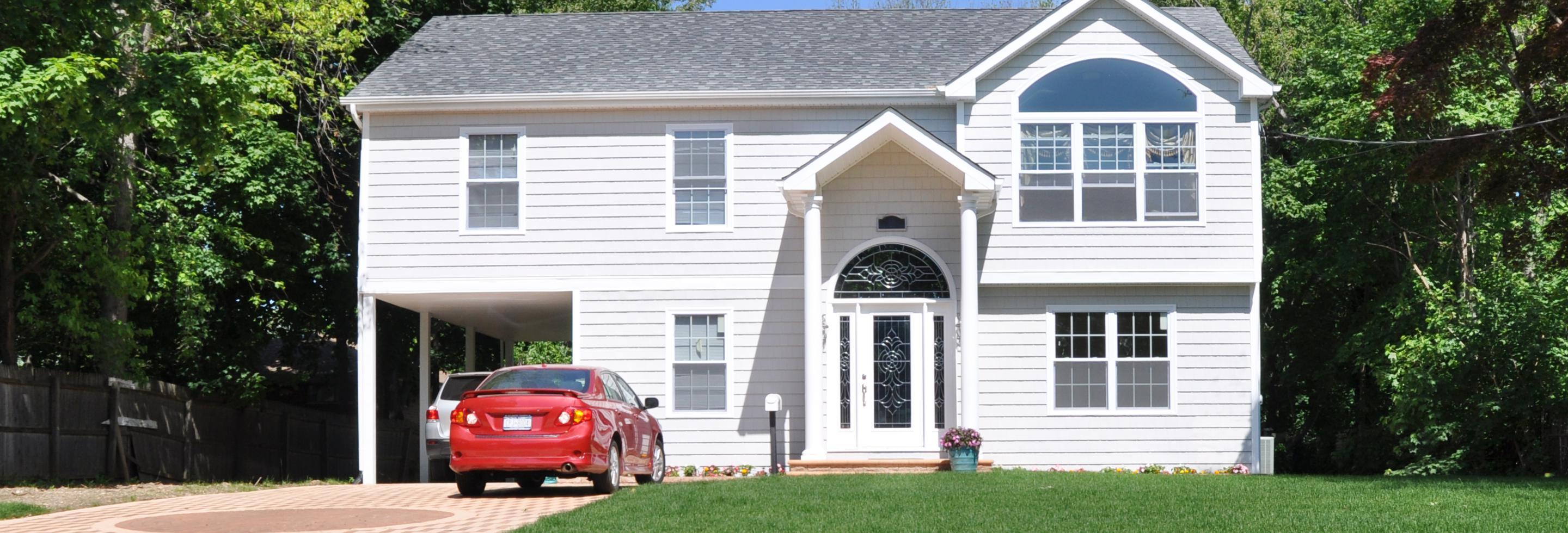 a white residential house with a red car