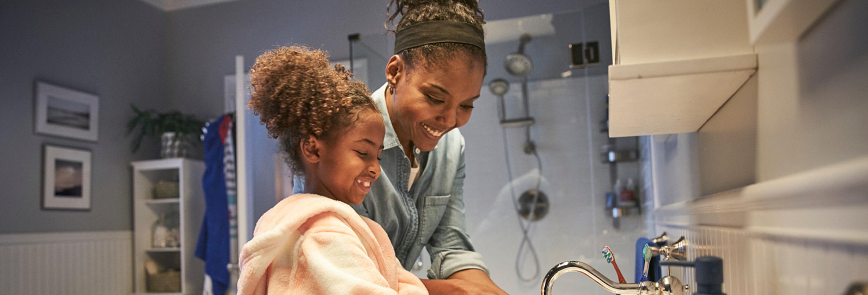 a mom and daughter at a sink