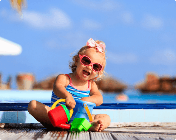 Happy baby playing with her toys on the beach. 