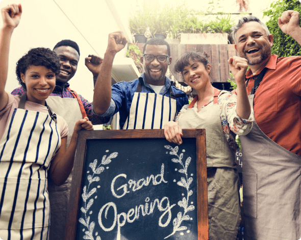 A smiling group of people holding a Grand Opening sign. 