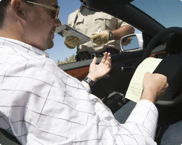 A driver pulled over on the side of the road getting a speeding ticket from a uniformed officer.