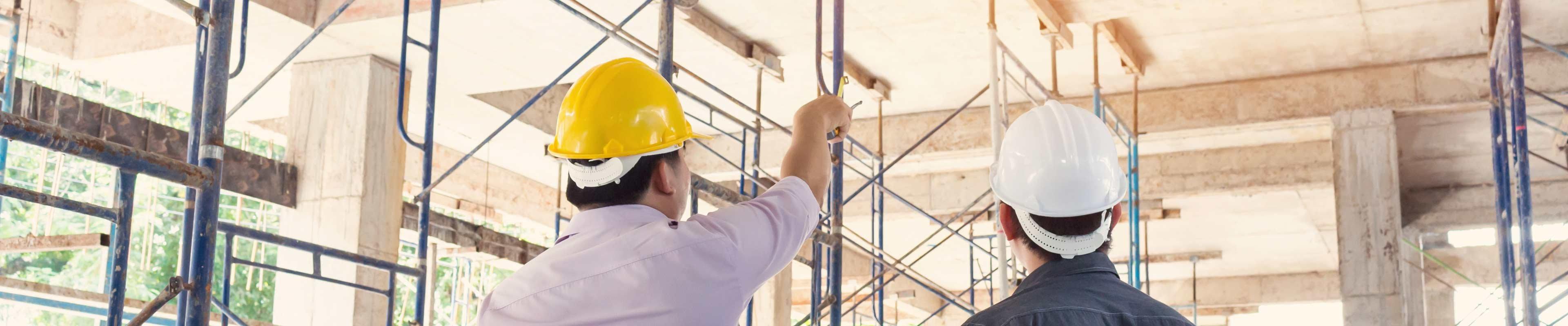 two men wearing hardhats looking at the inside of a building being constructed