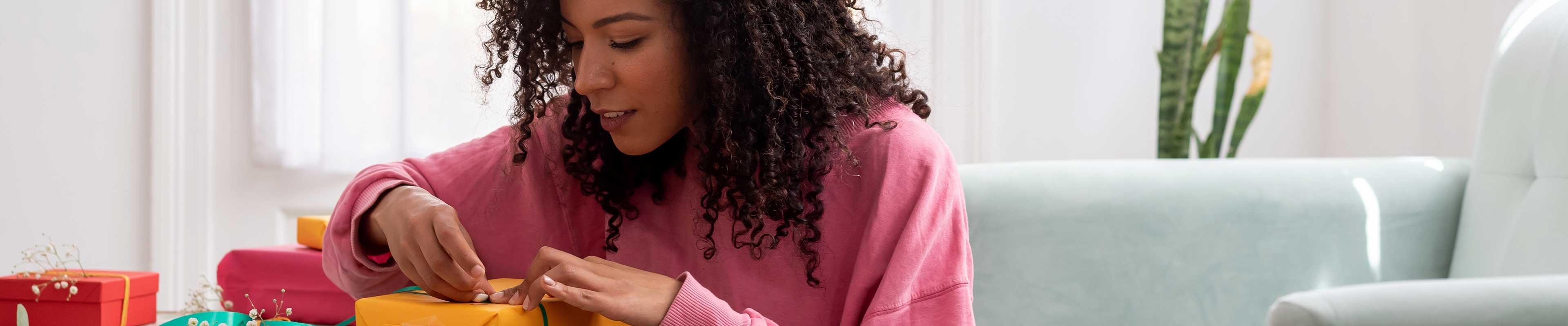 Young woman wrapping a gift for a celebration.