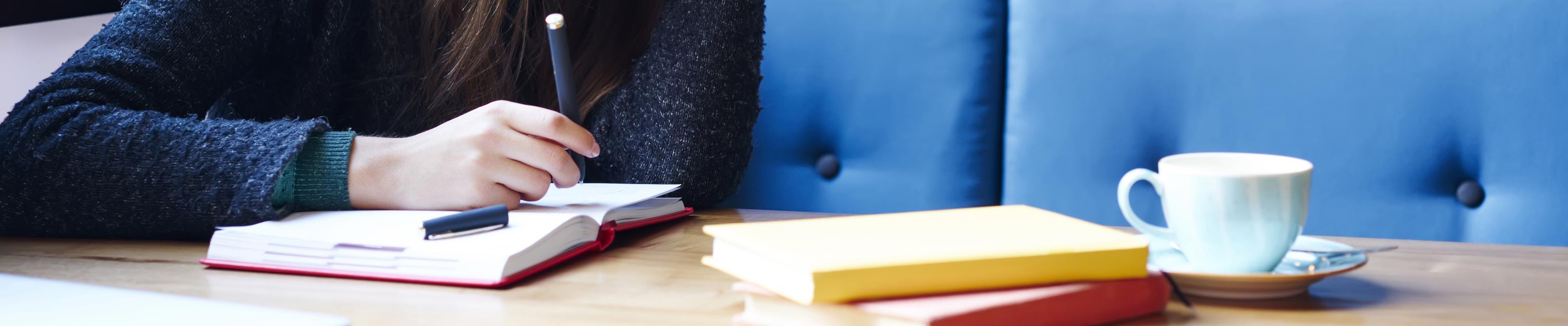 young woman sitting in a booth writing in a planner