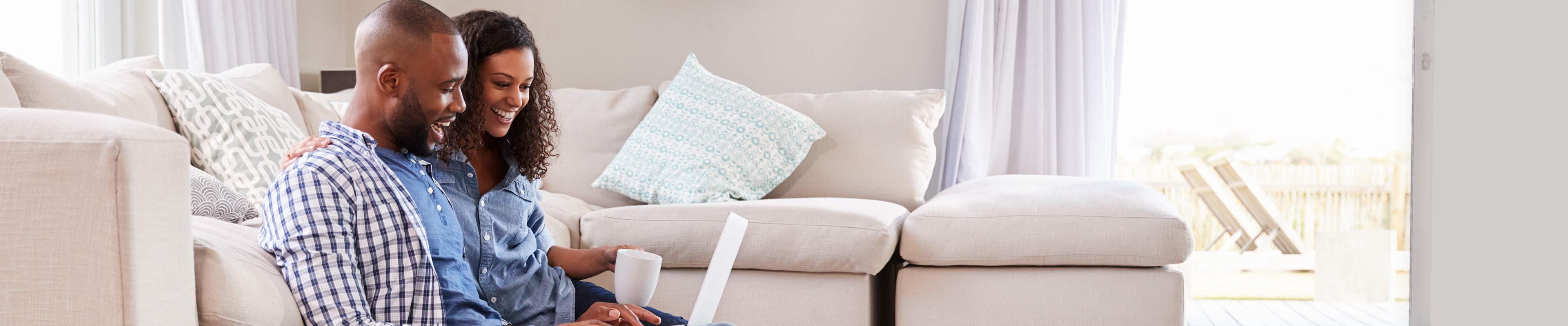 Young couple sitting on living room floor looking up how to switch homeowners insurance providers.