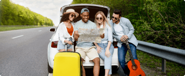 a group of four sitting on a trunk looking at a map