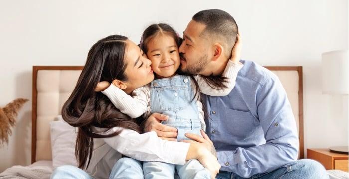 Father and mother kissing their child