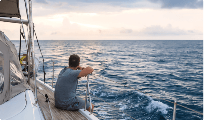 a person sitting on the side of a sailboat