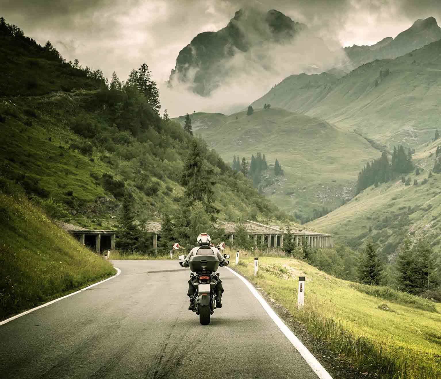 a person riding a motorcycle on a road in the mountains