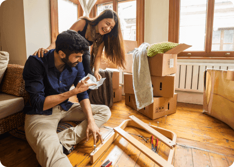 a man and woman sitting on a couch with boxes and a table